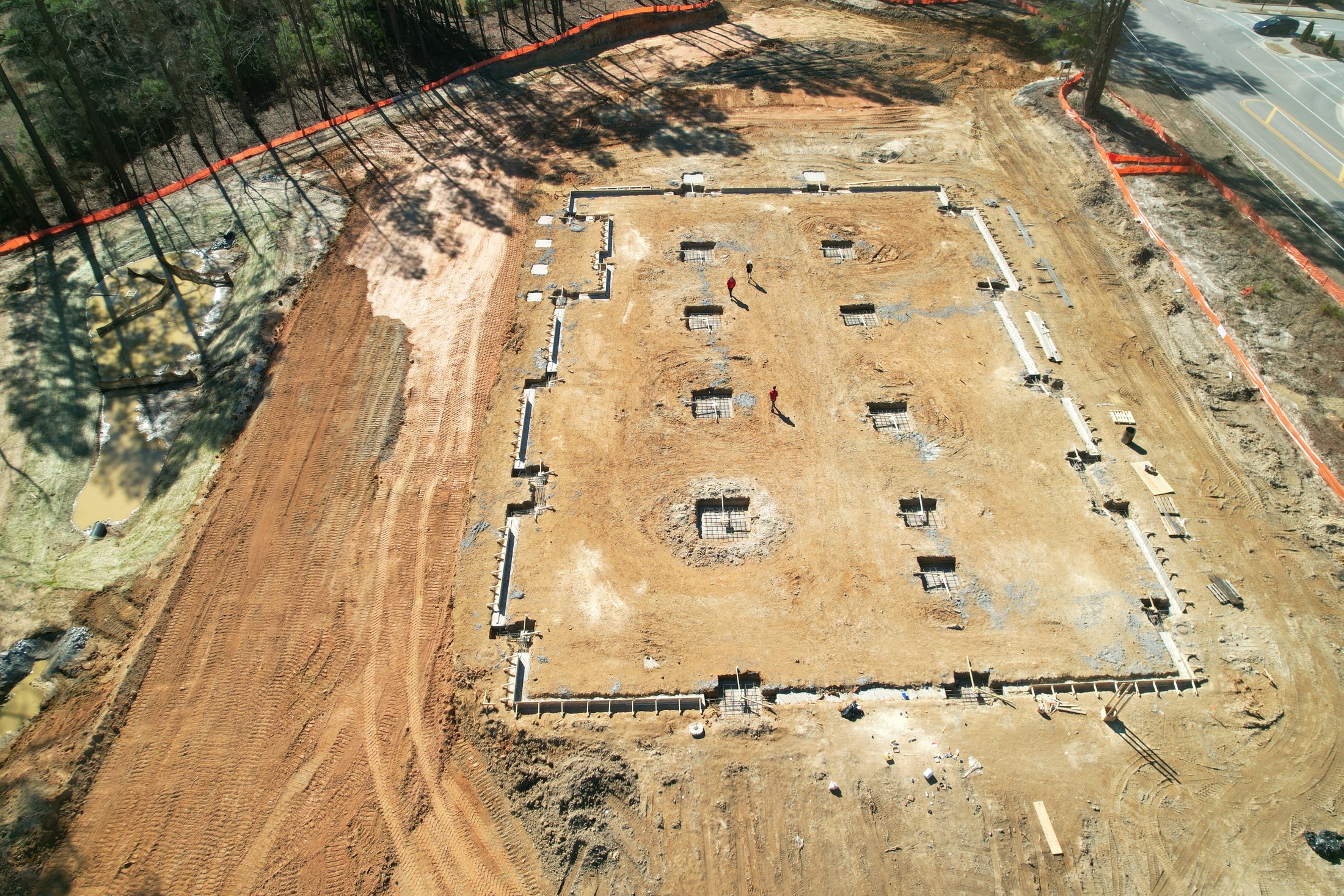 Top-down construction aerial showing a full cleared lot and foundation layout