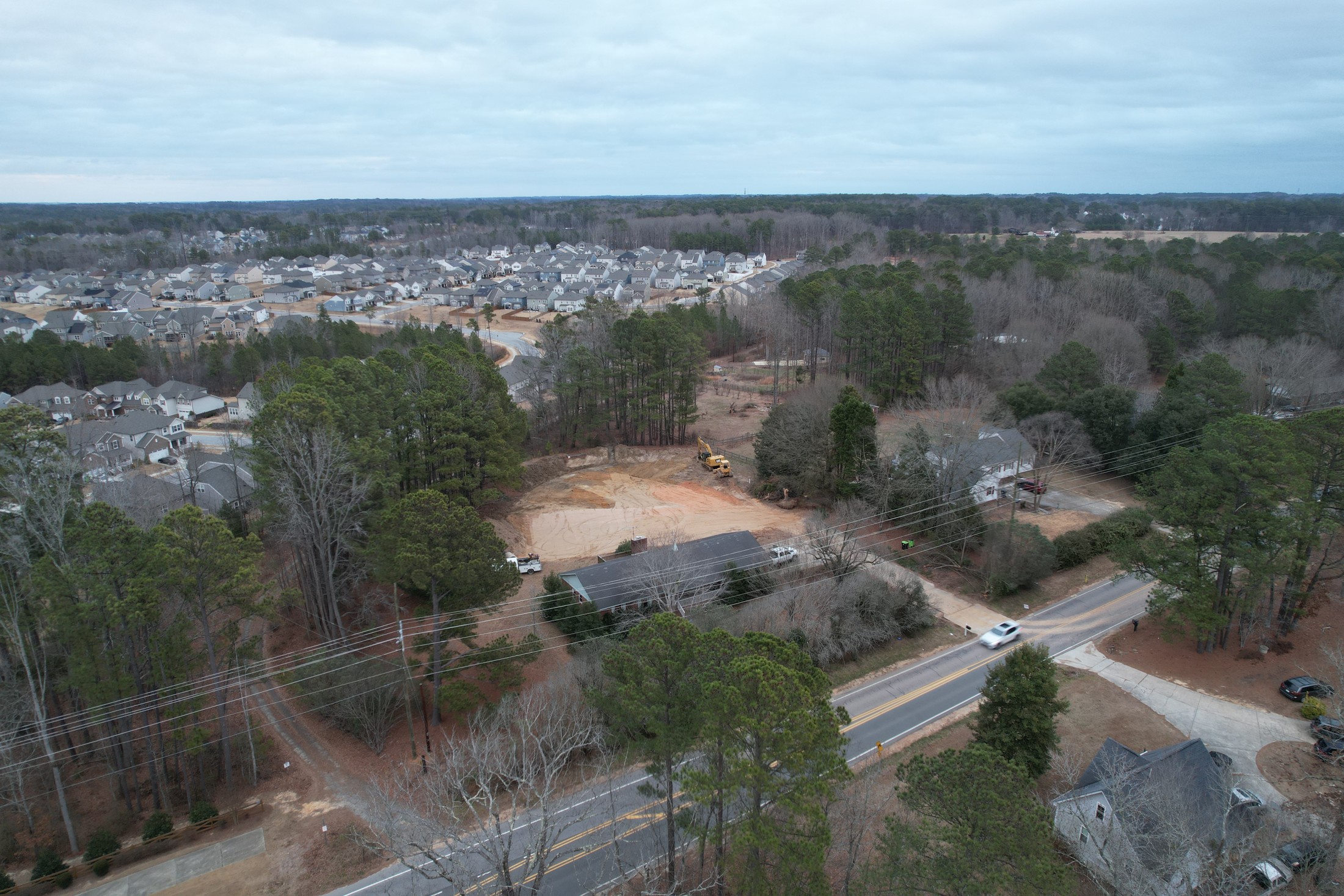 Wide neighborhood aerial showing homes, roads, and surrounding development