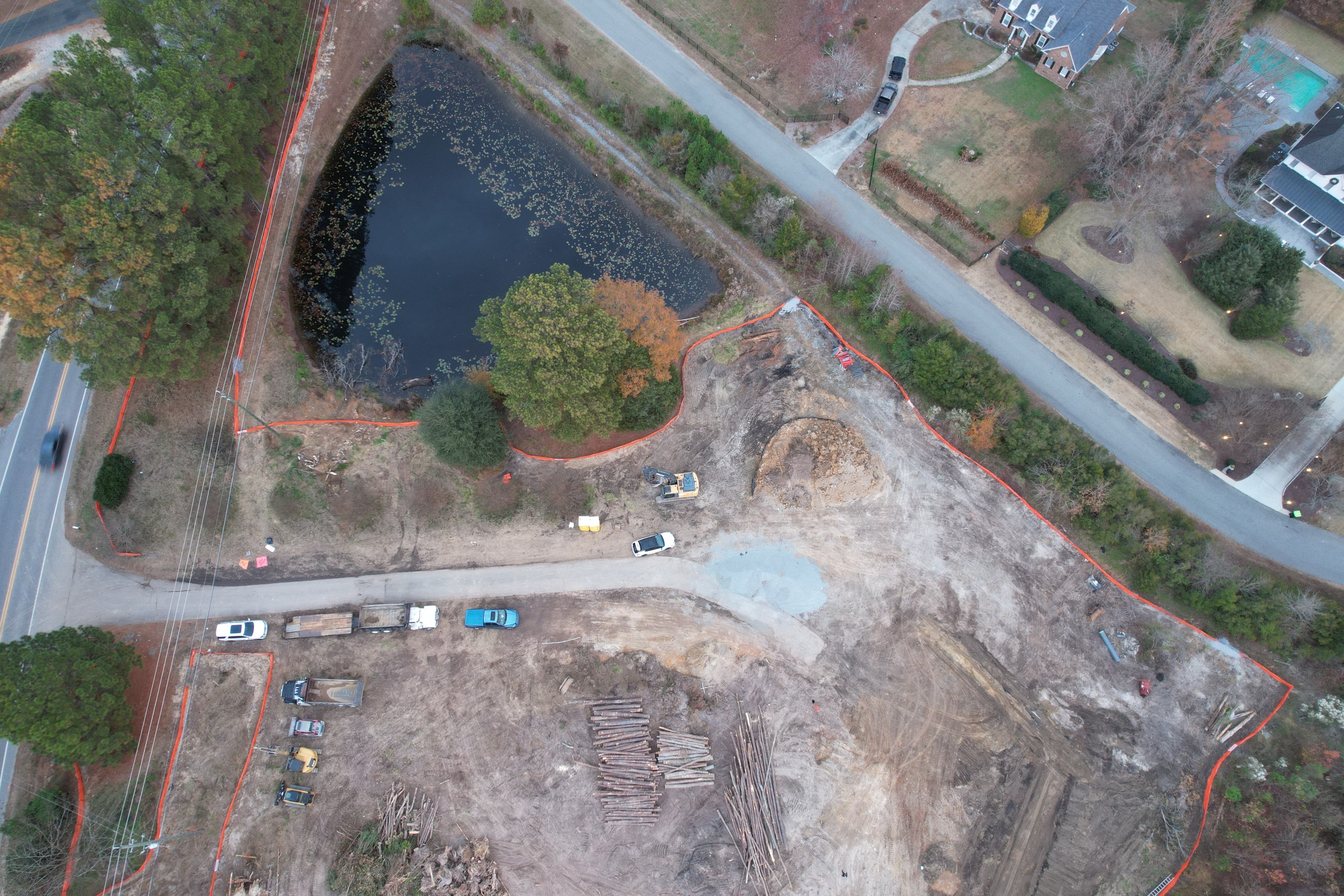 Aerial overview of a pond, road, and surrounding construction area