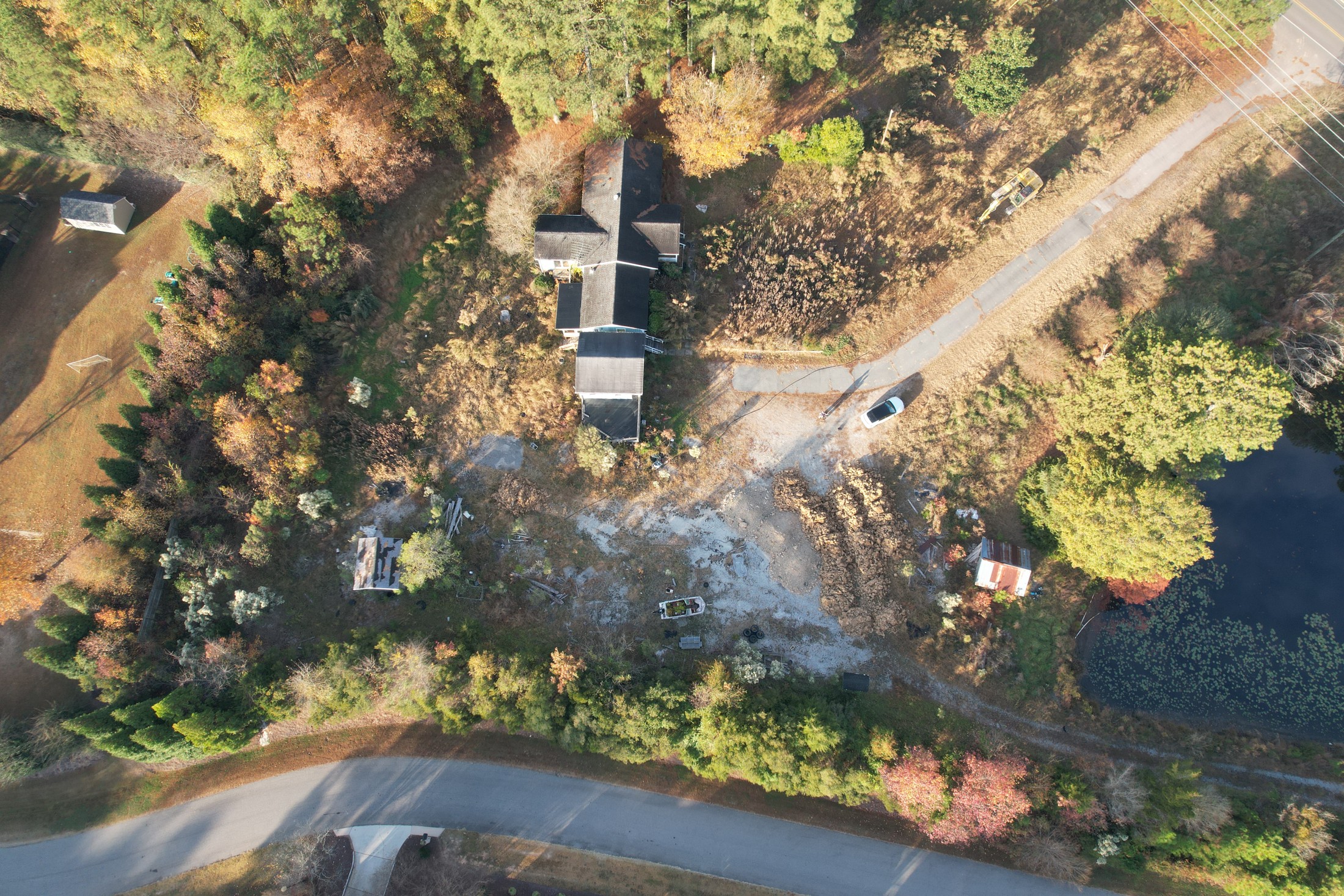 Overhead aerial showing a wooded site next to a road and open land